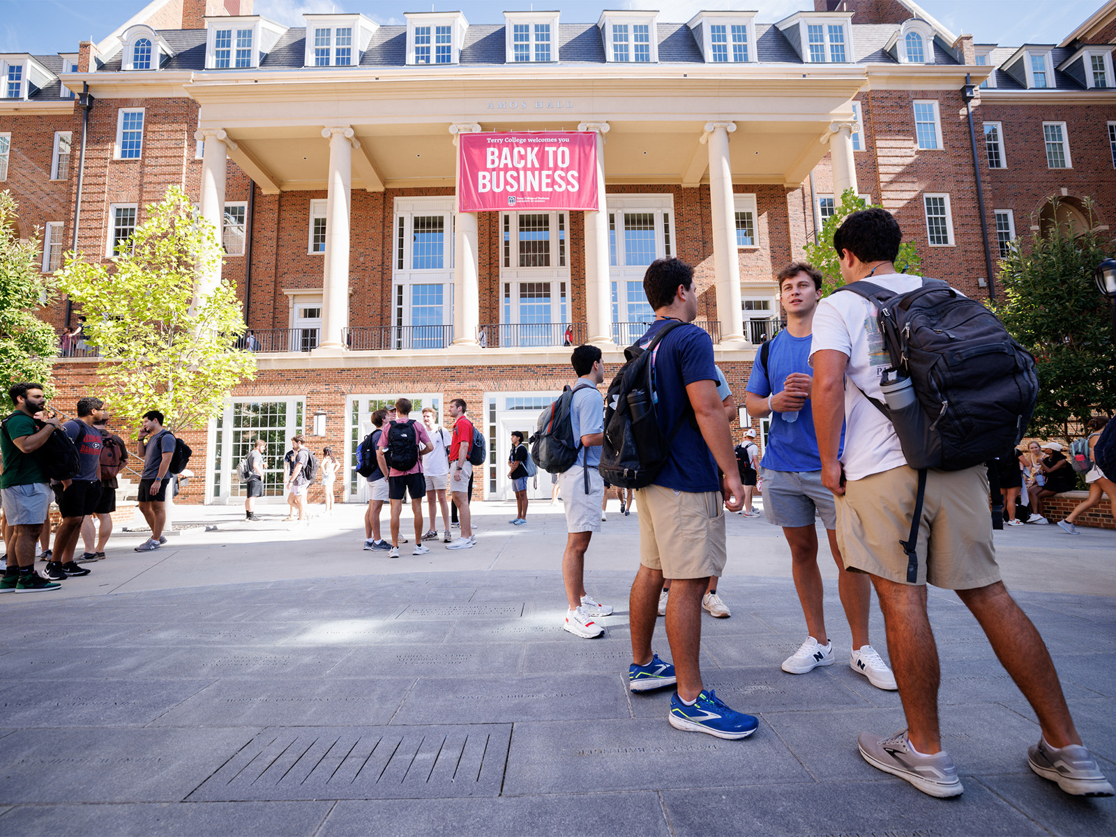 Students stand on CocCola plaza in front of ''Back to Business'' banner.